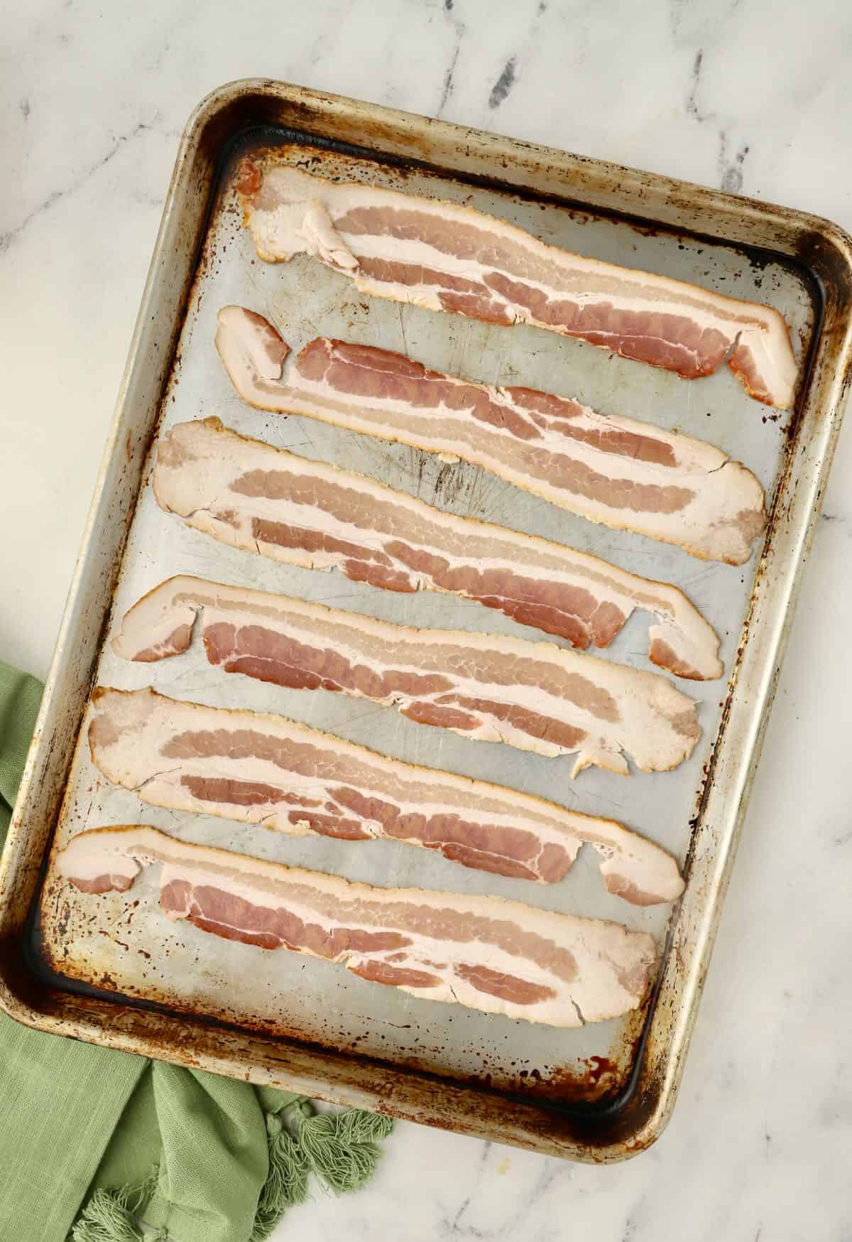 Slices of bacon on a baking sheet. 