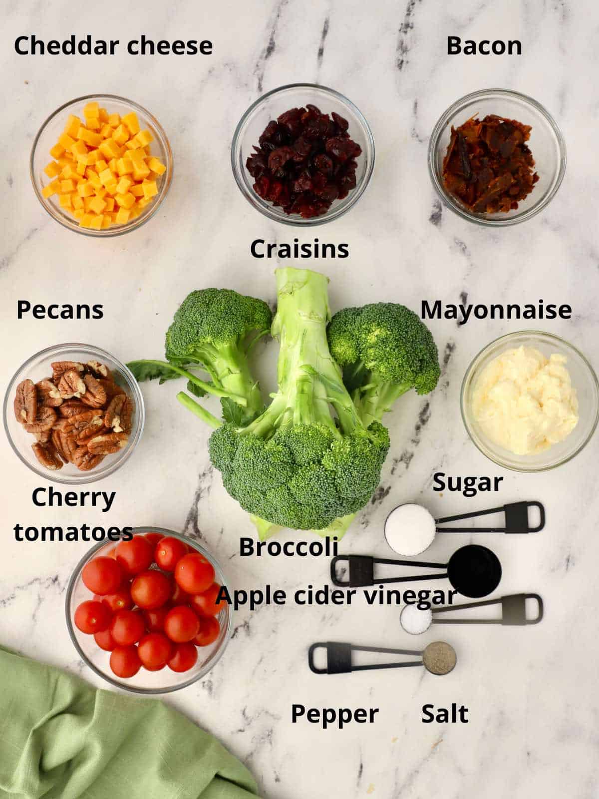 Ingredients for a broccoli salad including broccoli stalks, tomatoes, and craisins. 