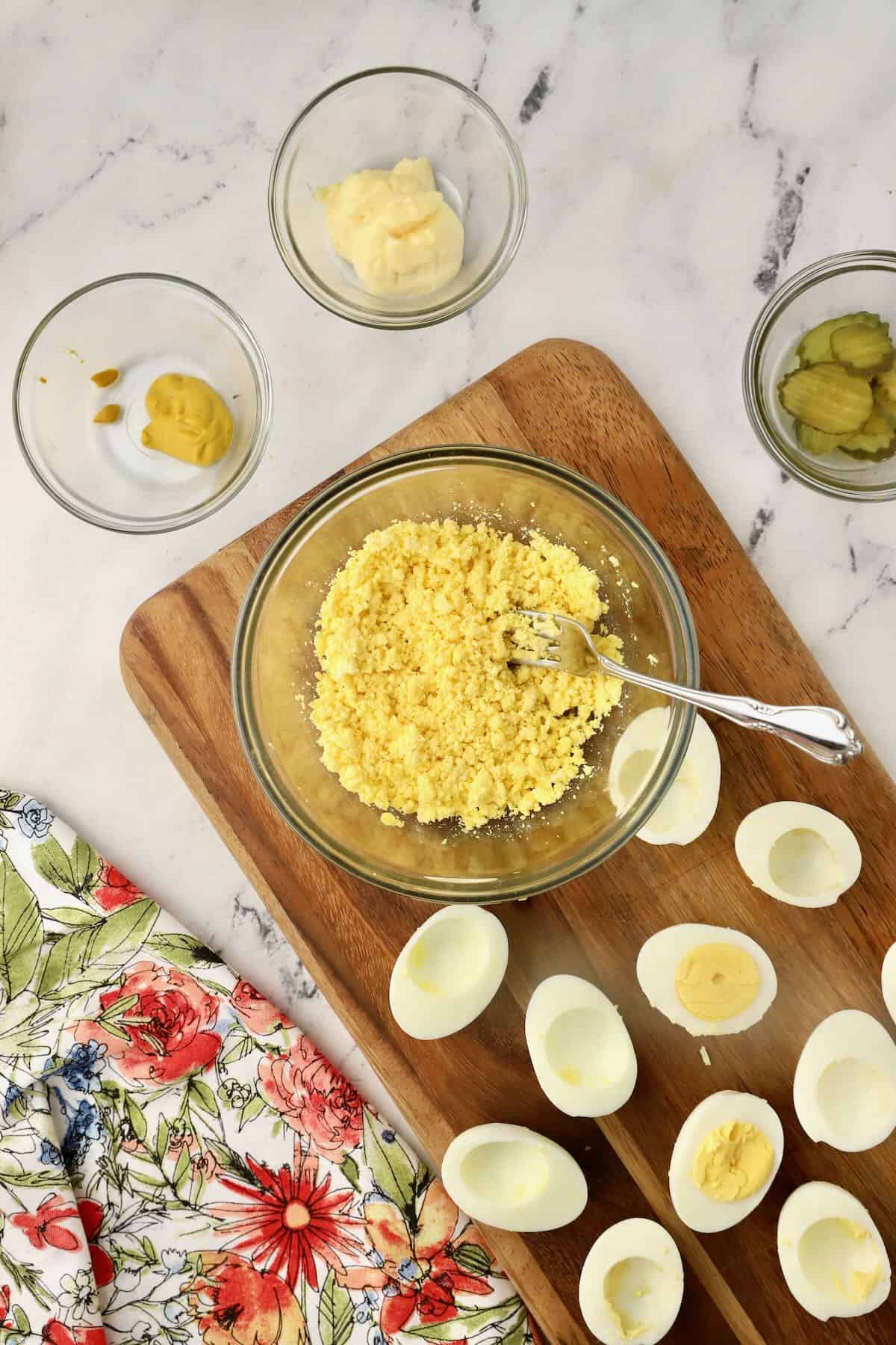 Using a fork to mash hard-boiled egg yolks. 