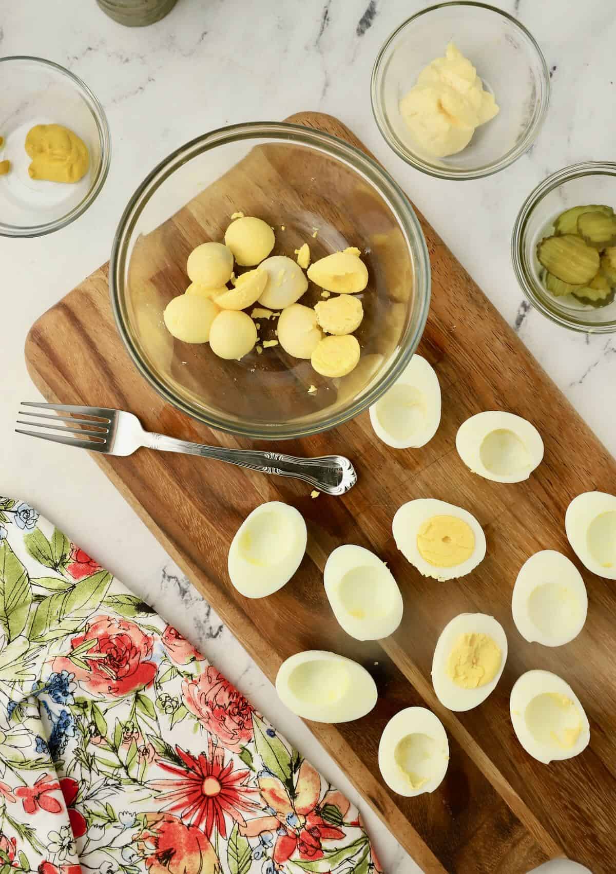 Hard boiled eggs sliced in half and the yolks in a bowl. 