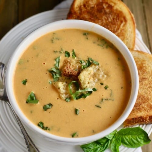 Roasted tomato soup in a white bowl topped with croutons.