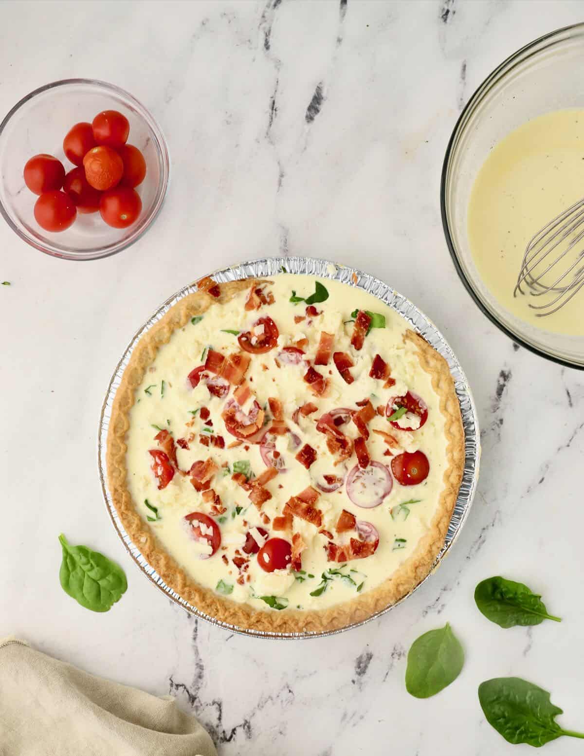 A quiche with an egg and cream filling topped with sliced cherry tomatoes. 