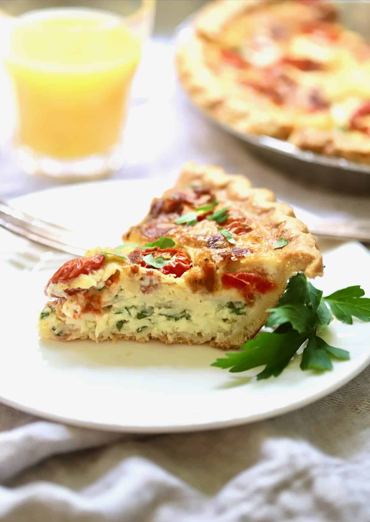 A slice of spinach and bacon quiche with tomatoes. 