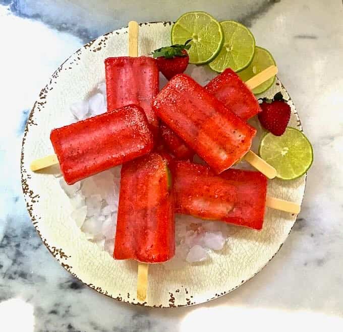 Strawberry margarita ice pops on a plate of ice. 