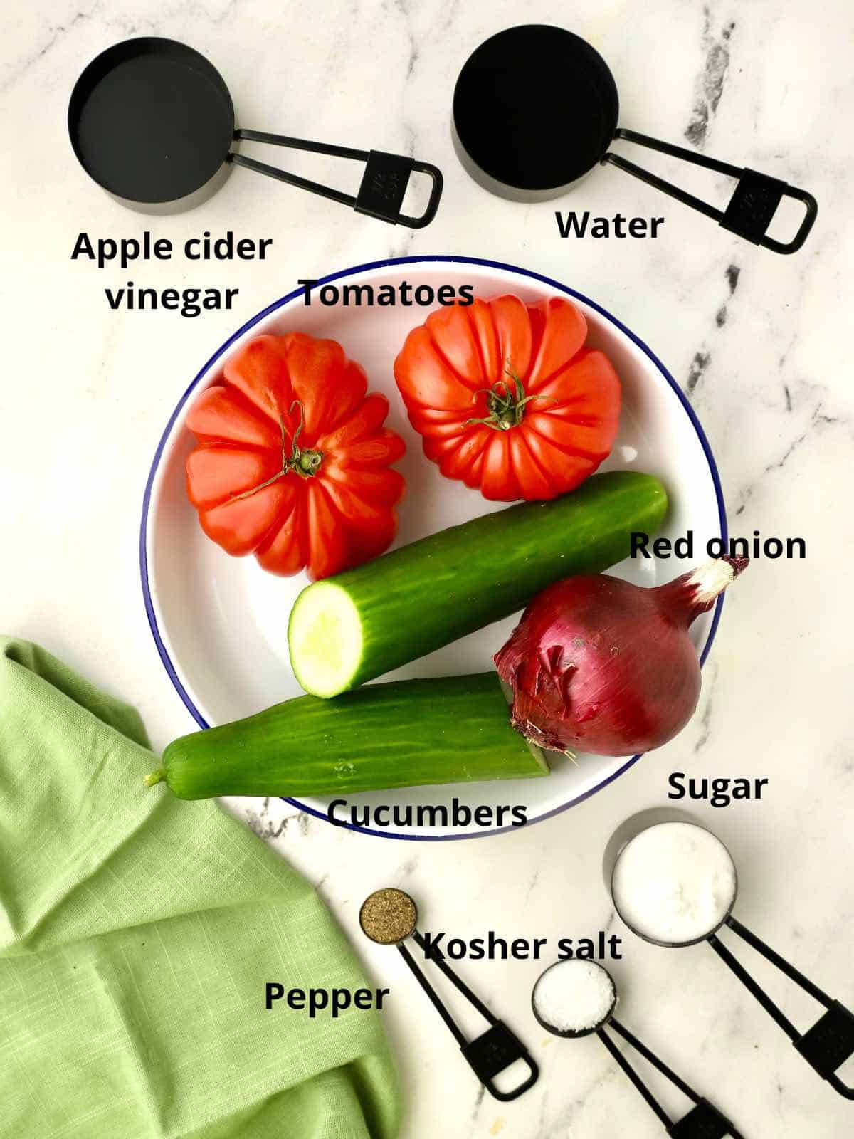Fresh tomatoes, cucumbers and onions plus ingredients to make a salad dressing. 