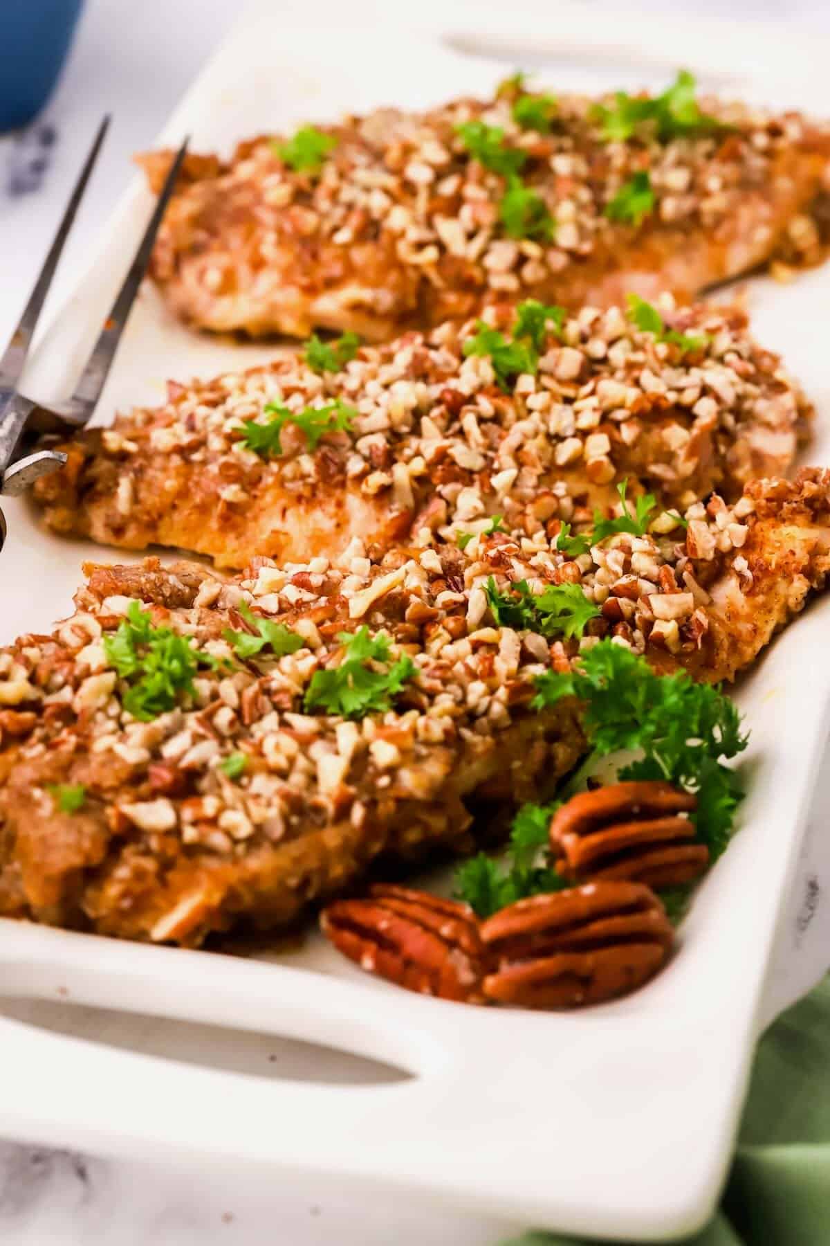 Three pecan crusted chicken breasts on a plate. 