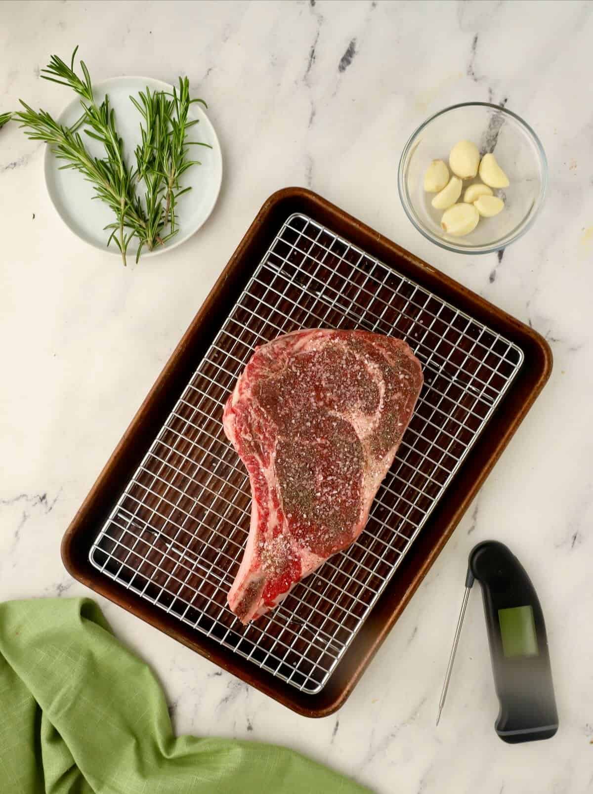 A ribeye steak on a wire cooking rack.