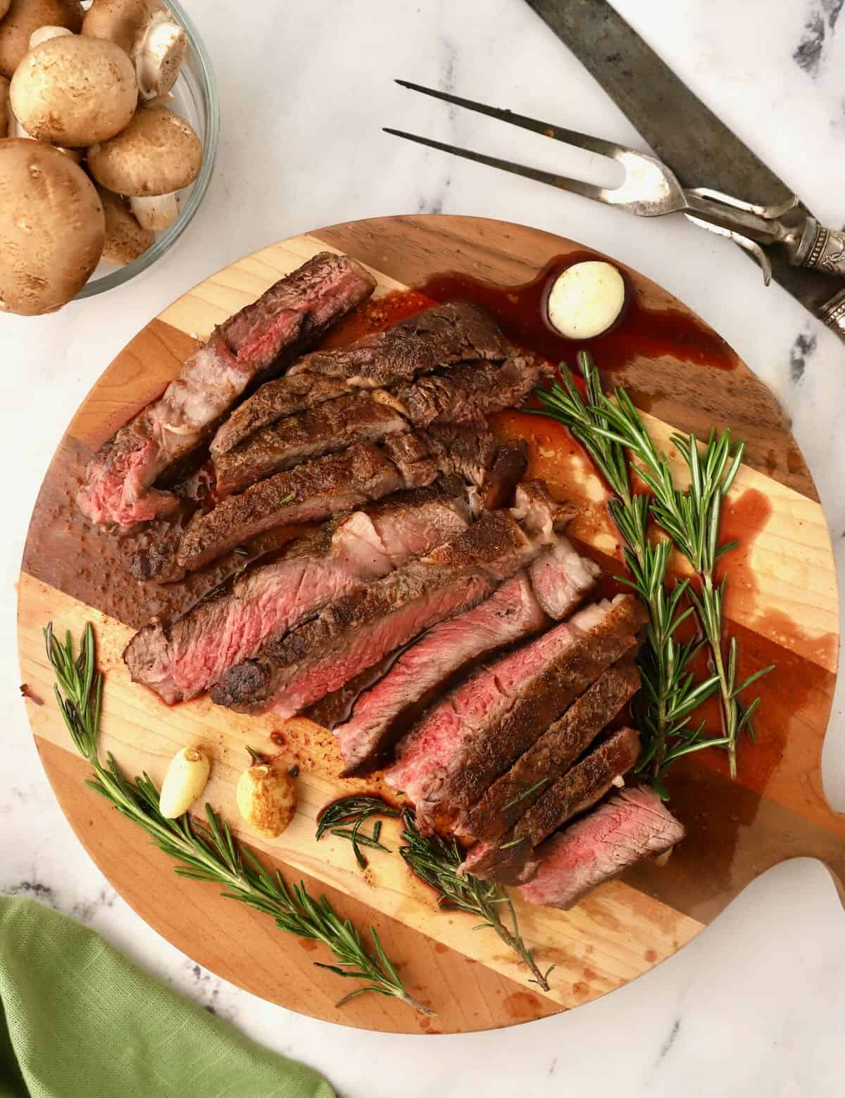 A reverse seared ribeye steak sliced on a cutting board. 