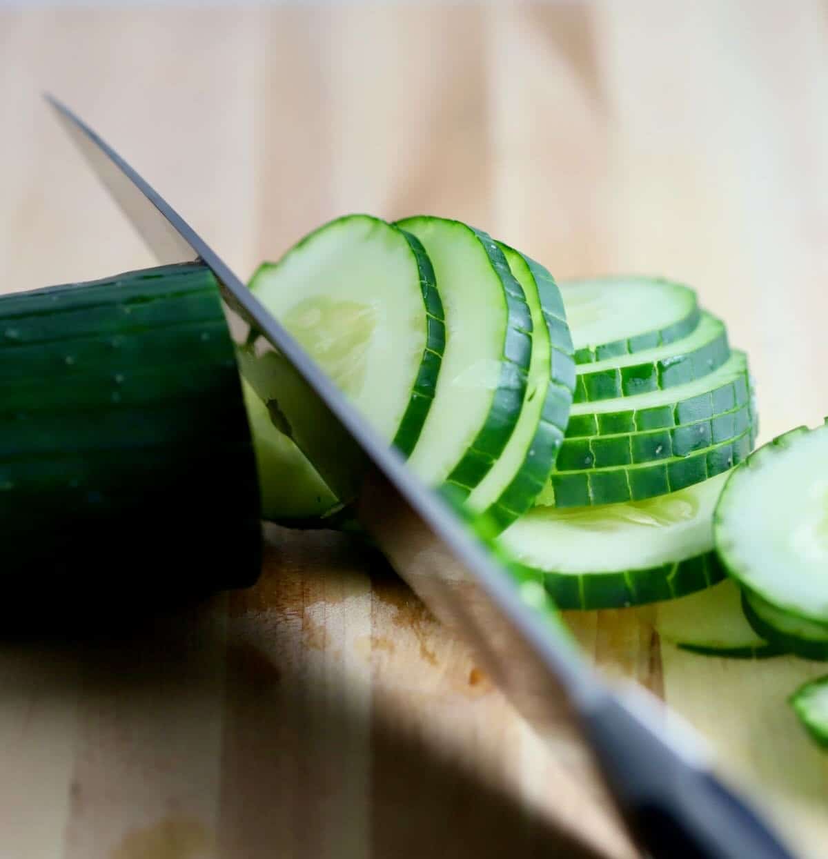 Using a knife to cut a cucumber into slices. 