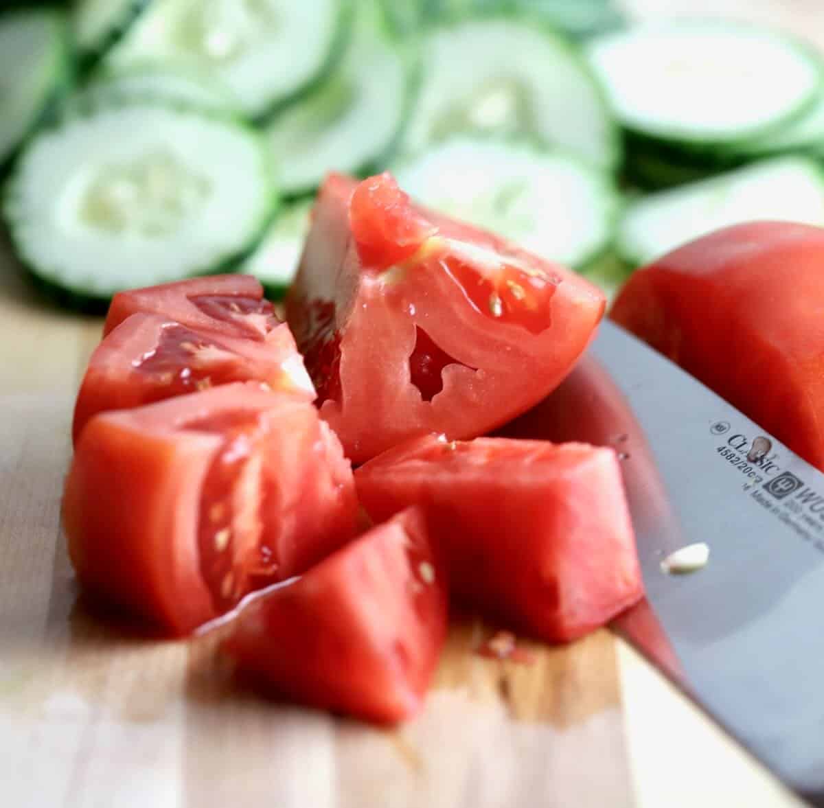 Using a knife to cut a tomato into large chunks. 