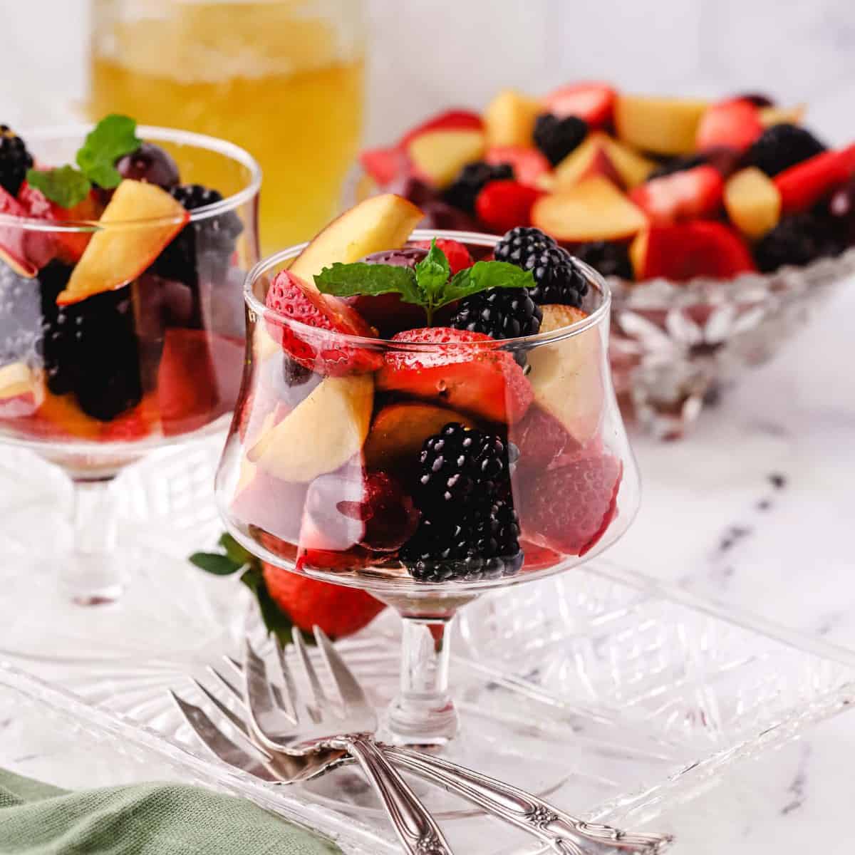 A glass dish full of a mixed fruit salad.