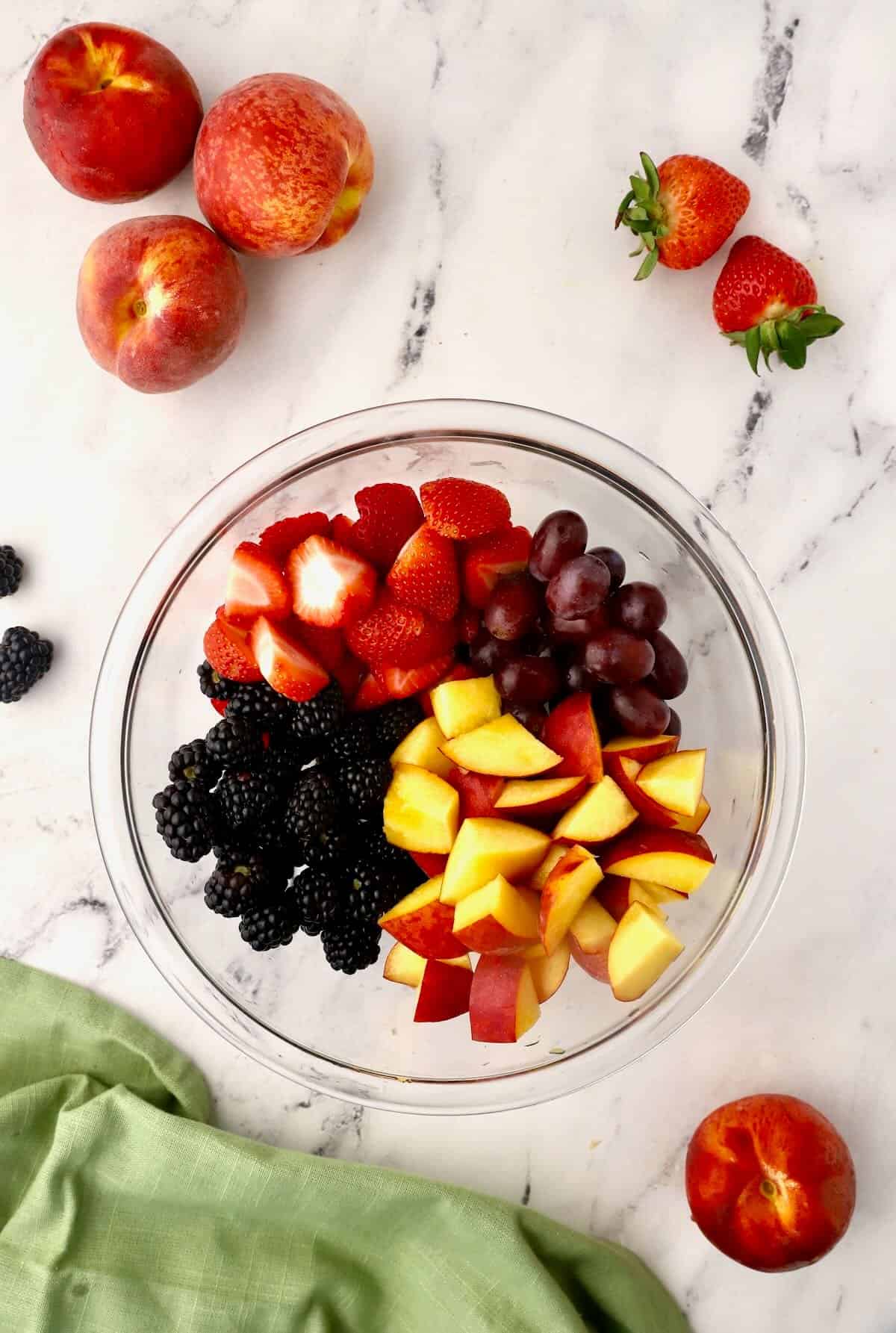 A bowl of peaches, strawberries, and grapes.