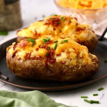 Two loaded twice baked potatoes topped with cheese and bacon.