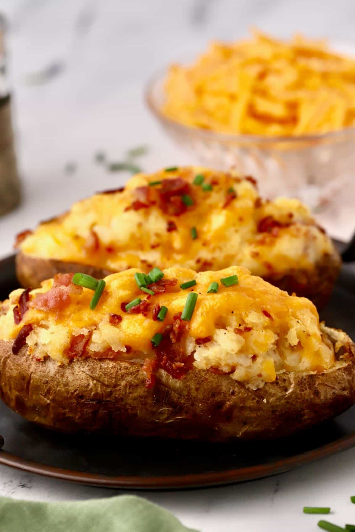 Two loaded twice baked potatoes on a plate.