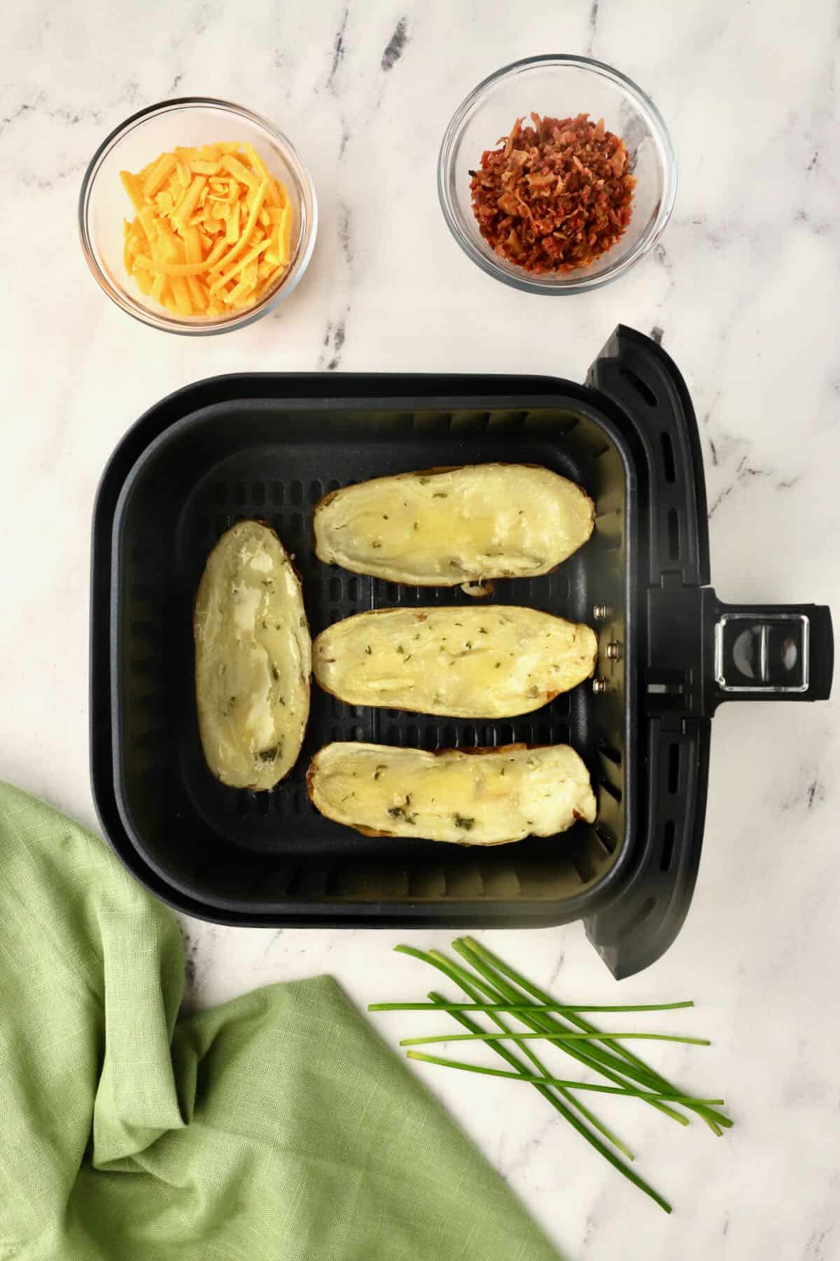 Potato skins in the basket of an air fryer. 