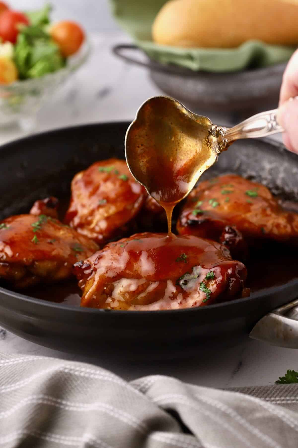 Honey baked chicken thighs in a cast iron skillet with a honey glaze spooned over them. 