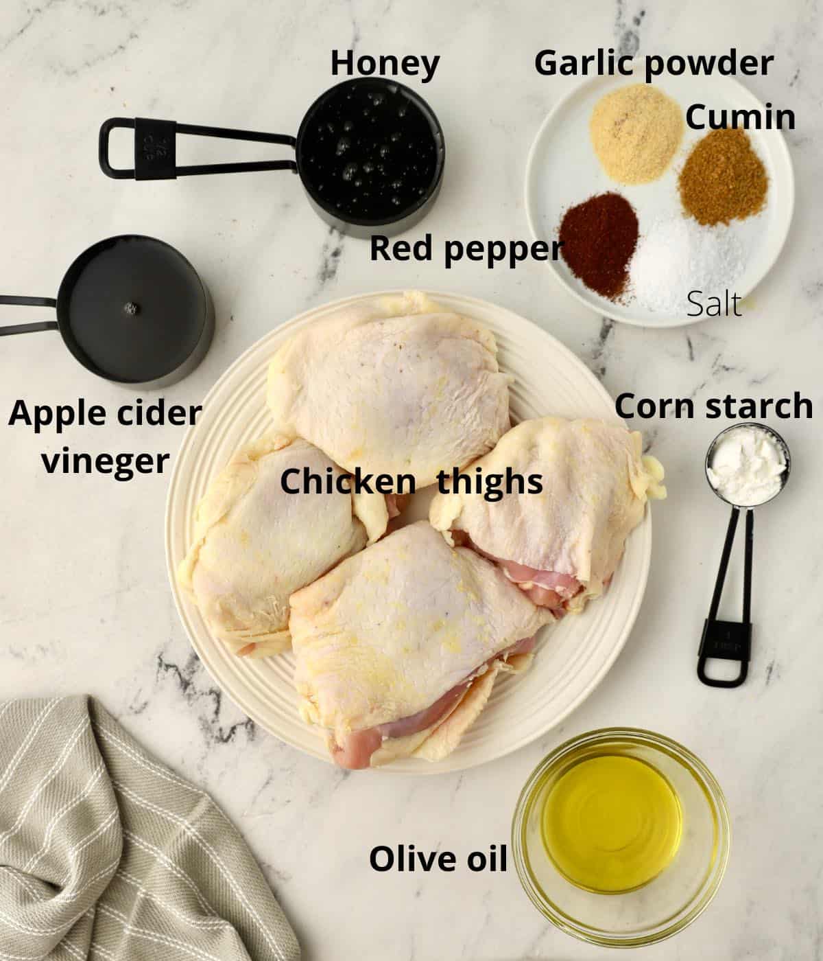 A plate with raw chicken thighs and other ingredients to make honey glazed chicken thighs. 