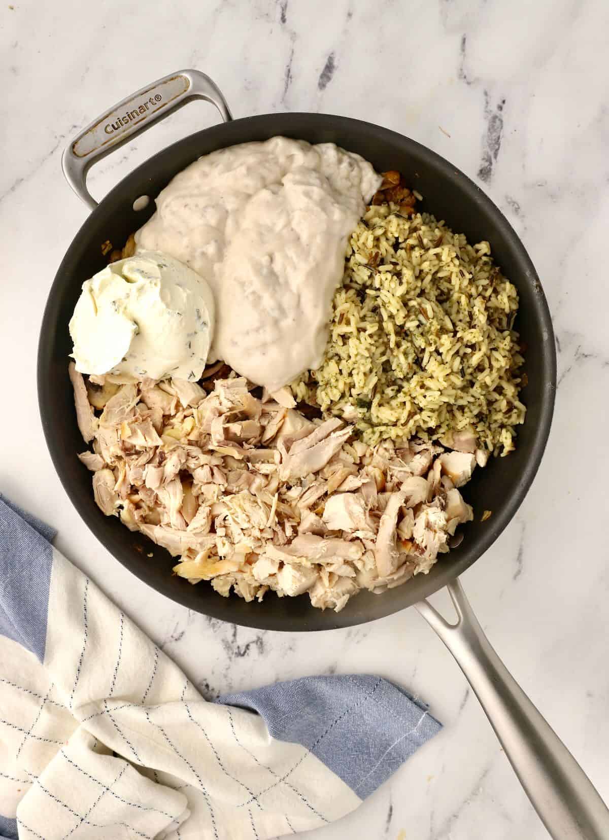 A skillet with sausage, chicken, rice, soup and cream cheese. 