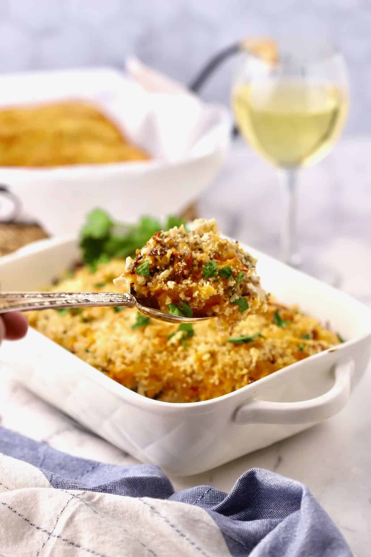 A large spoonful of chicken, sausage and rice casserole  next to the baking dish. 