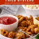 Pinterest pin showing fried oysters on a plate with a bowl of cocktail sauce.
