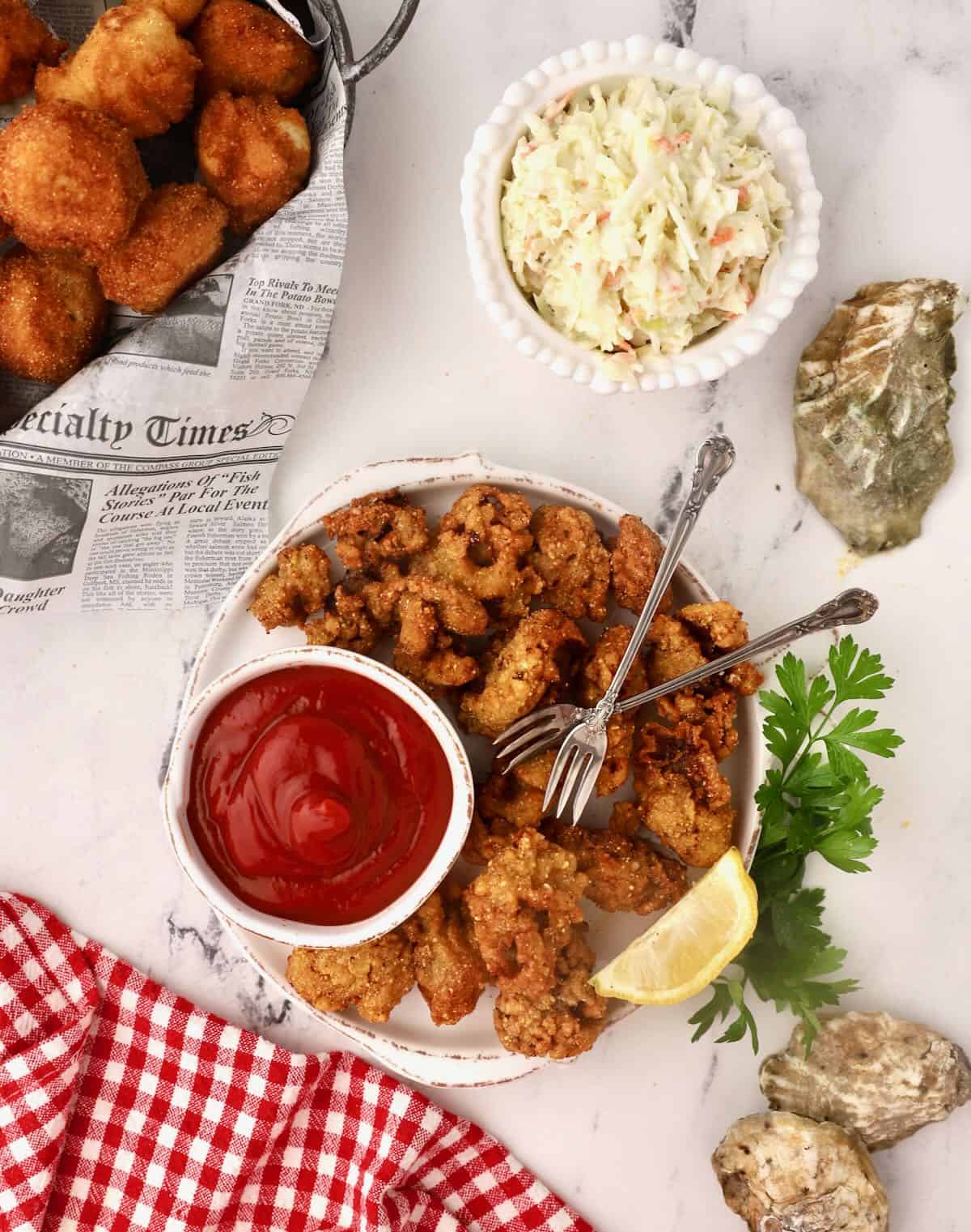 A plate of fried oysters, coleslaw, and hush puppies.