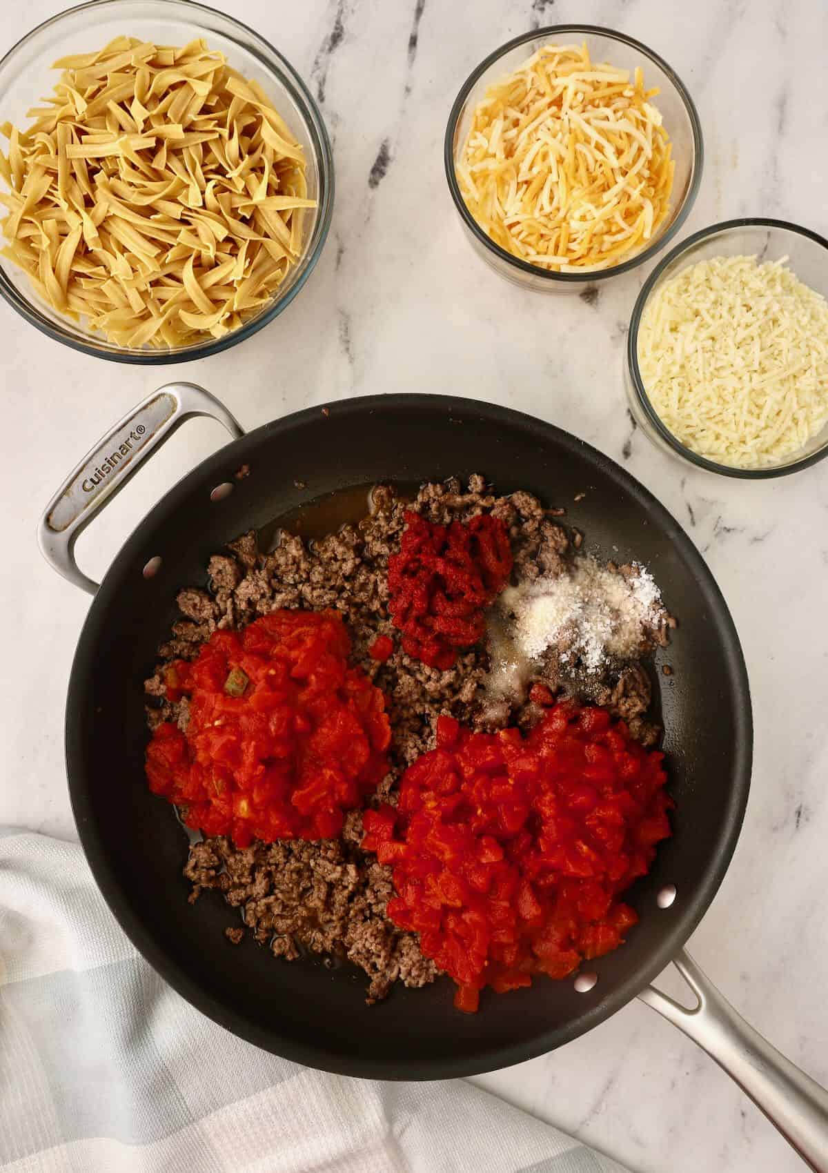 Adding canned tomatoes to a skillet with ground beef. 