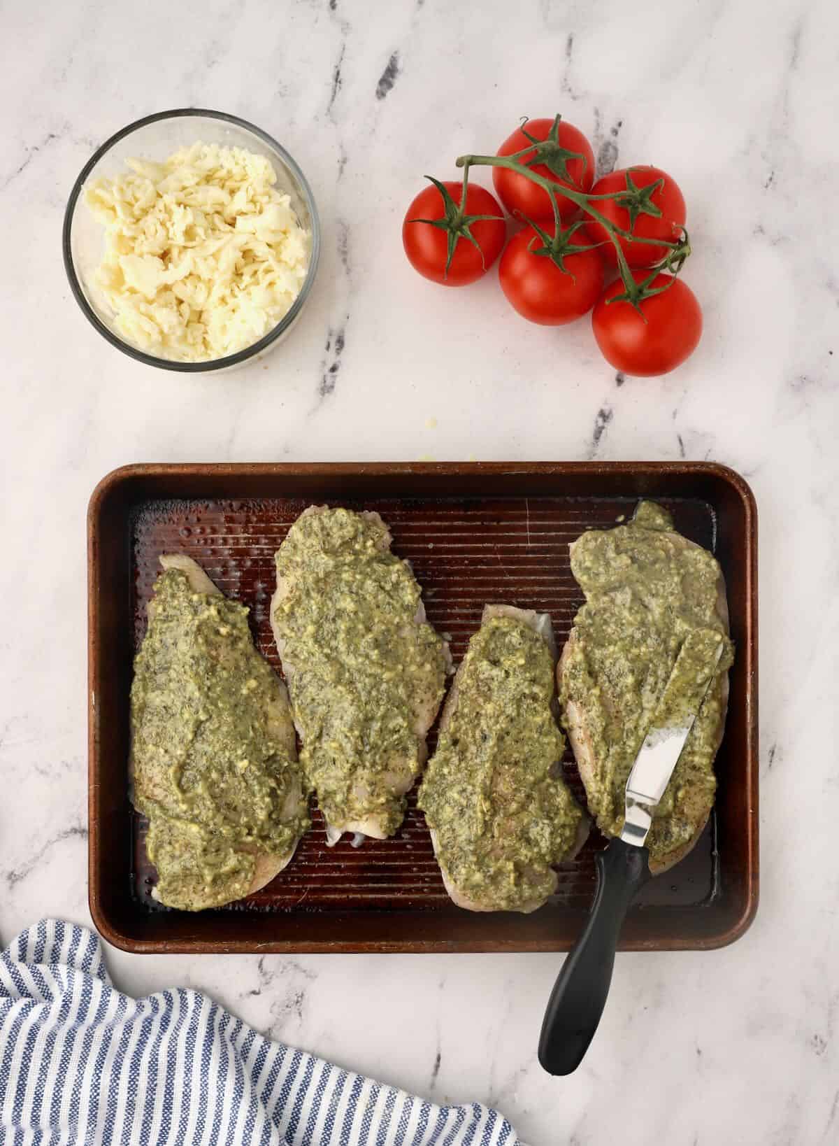 Four chicken breasts topped with basil pesto. 