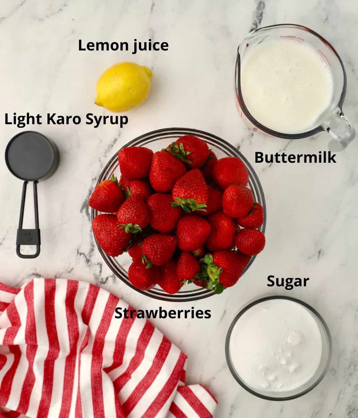A large bowl of strawberries plus other ingredients to make ice cream.