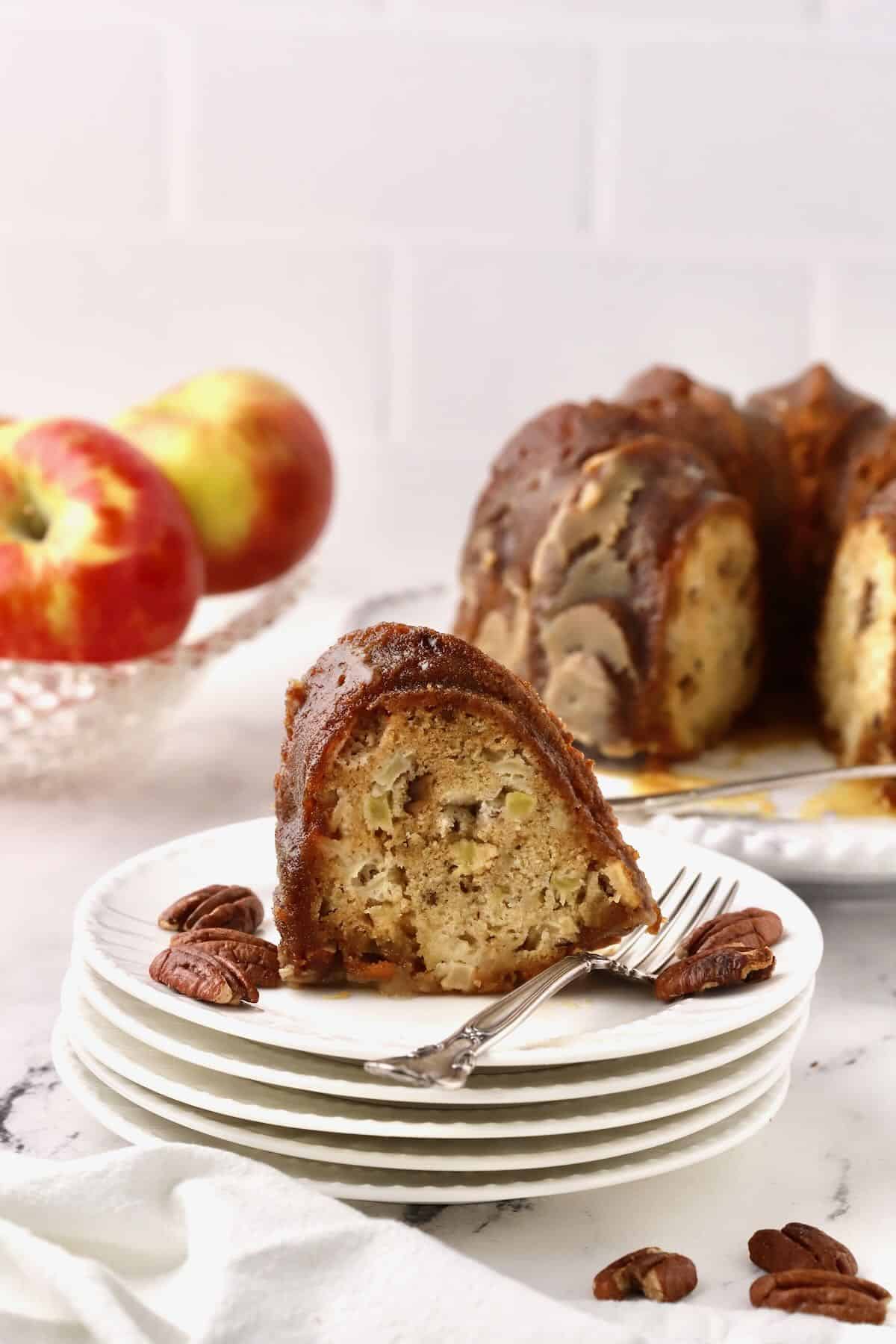 A slice of apple cake on a stack of white plates. 