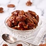 A clear cut glass dish full of candied pecans.