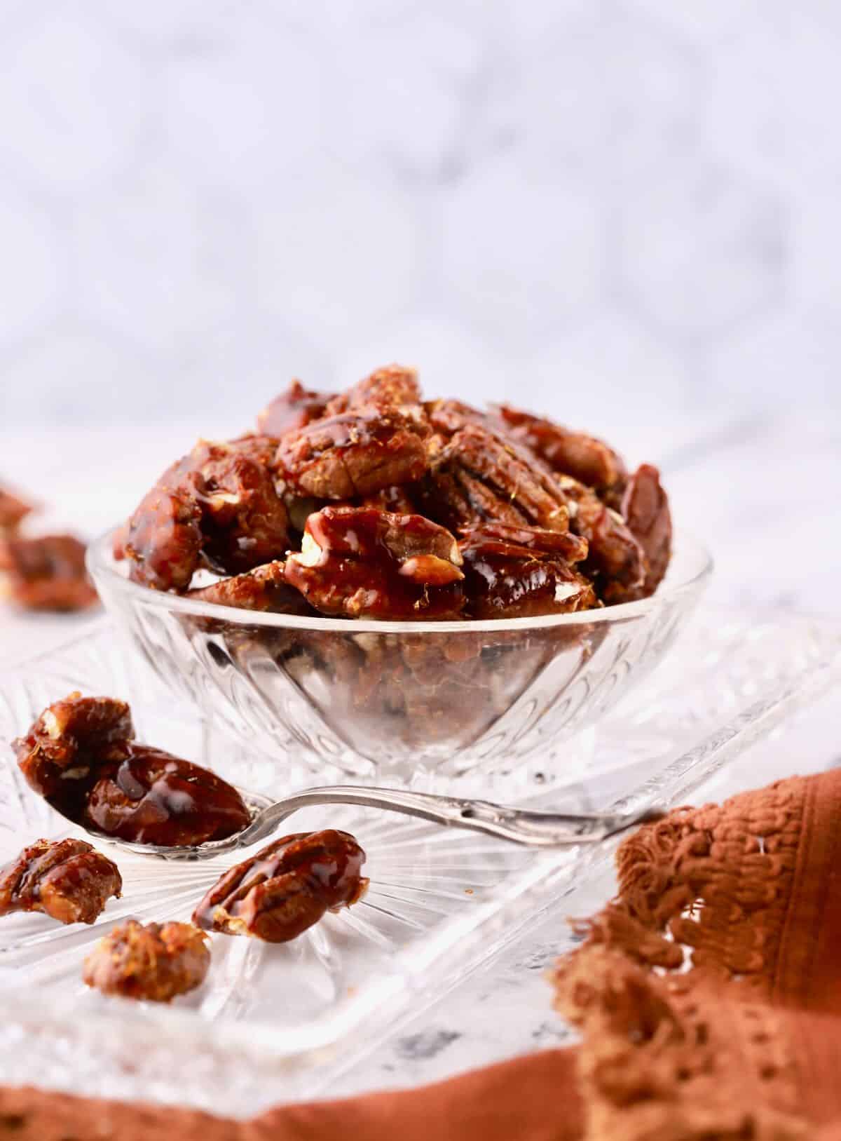 Candied pecans in a glass serving dish. 