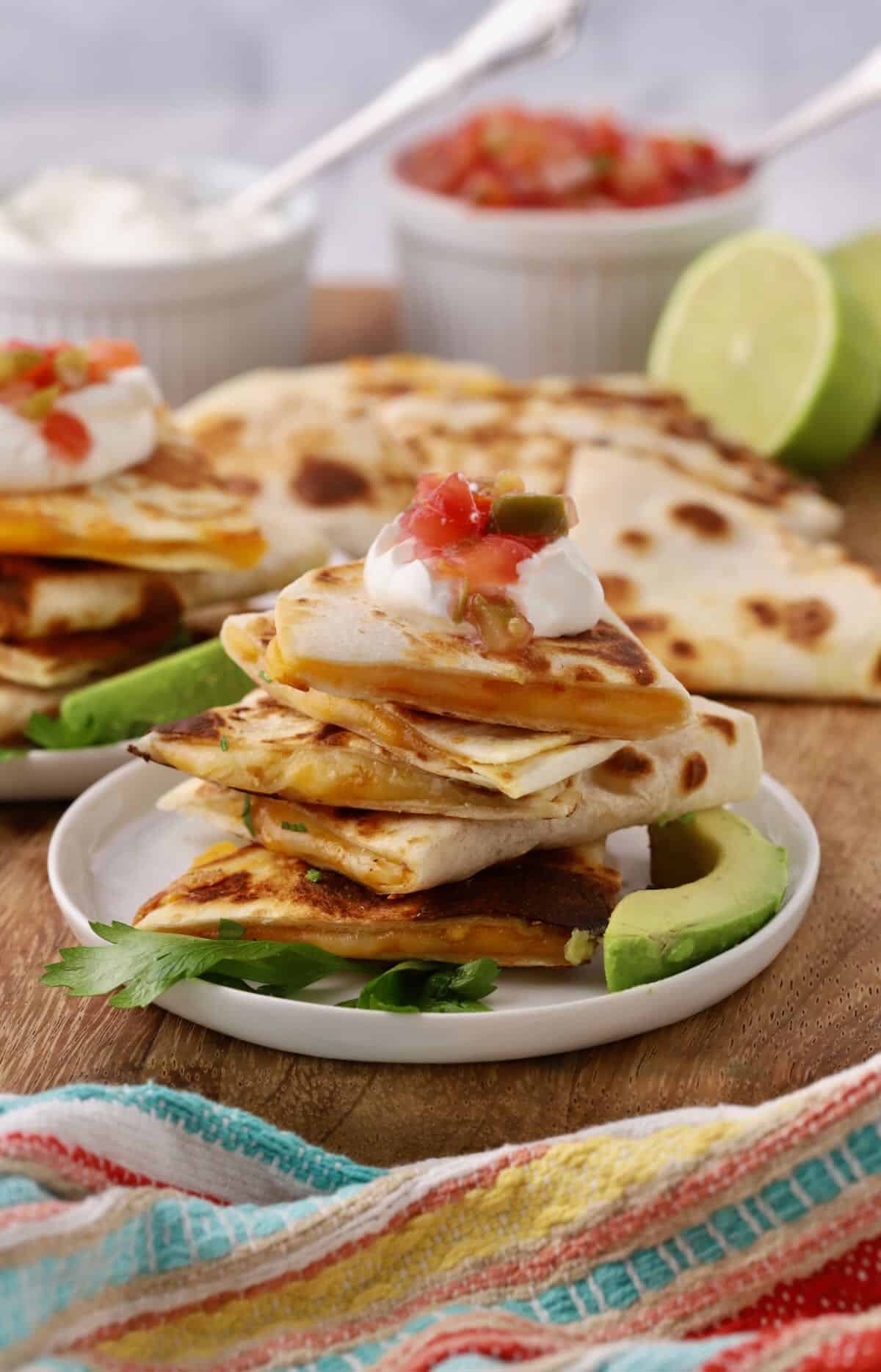 A stack of quesadillas topped with sour cream and salsa.