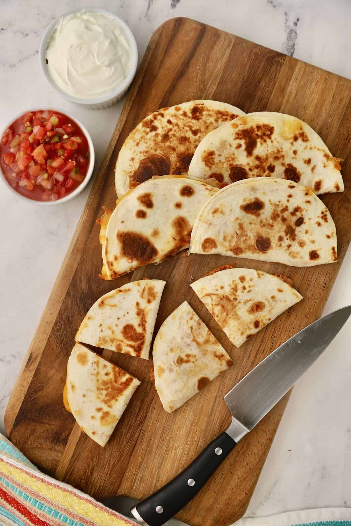Cutting cheese quesadillas into wedges with a knife. 