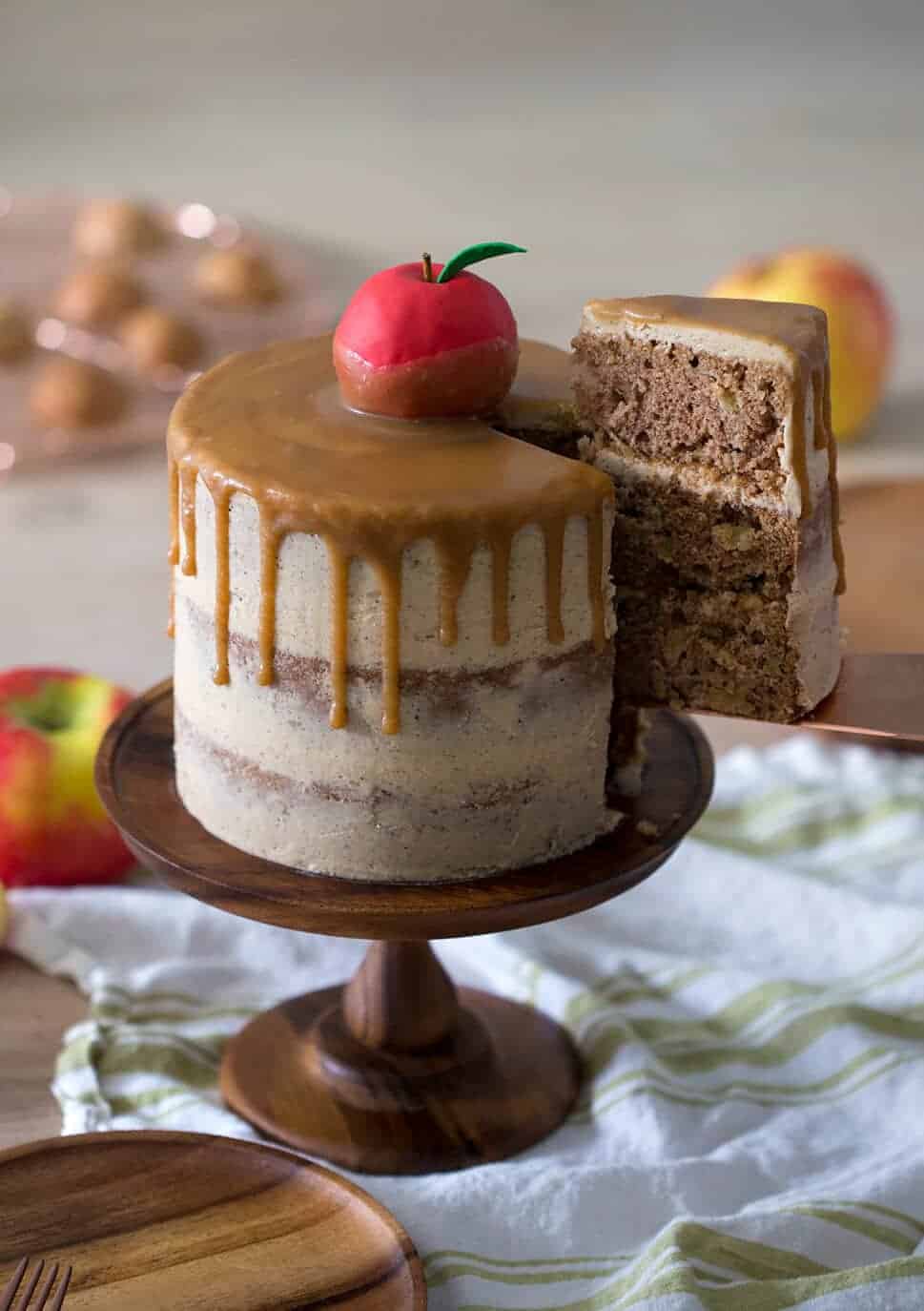 Apple cake on a wooden pedestal topped with an apple. 