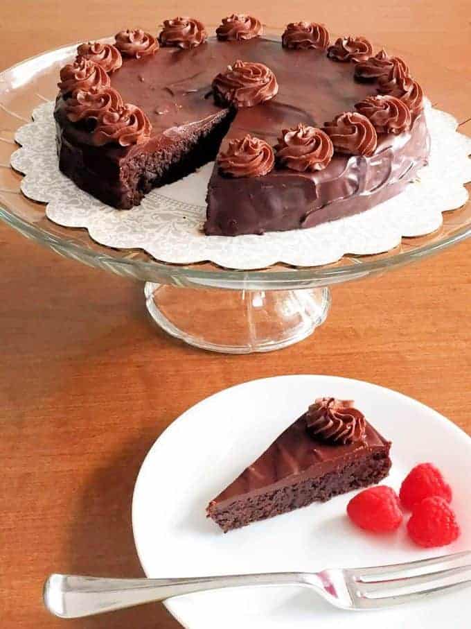 Flourless chocolate cake on a white pedestal cake plate.  