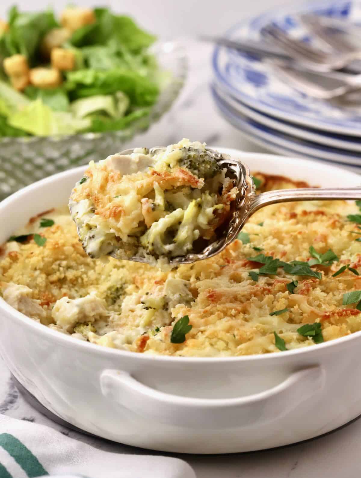 A large spoonful of chicken divan above the casserole. the