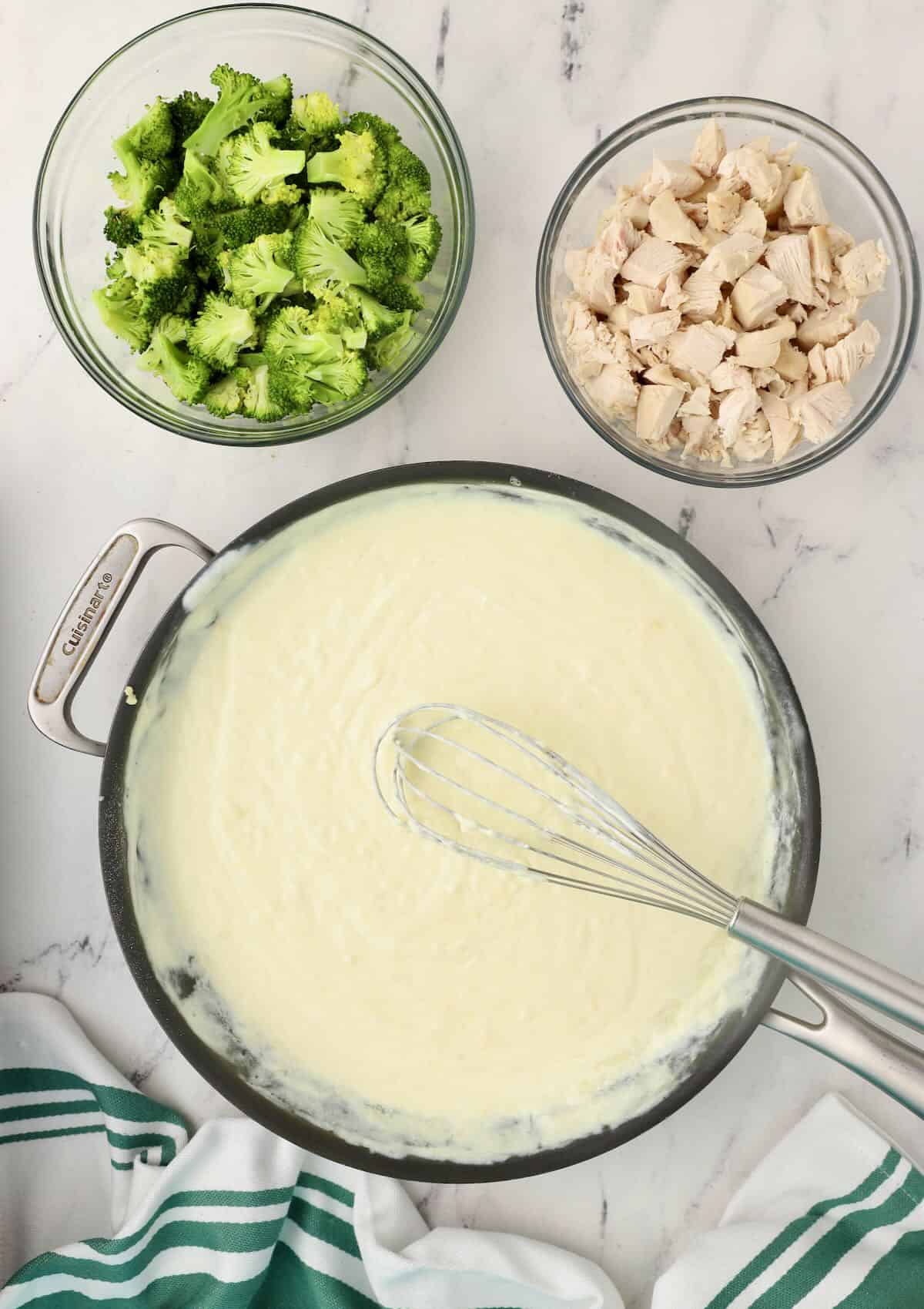 Making mornay sauce in a large skillet with bowls of chicken and broccoli nearby. 