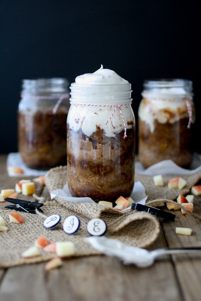 Mason jars full of apple pie and whipped cream. 