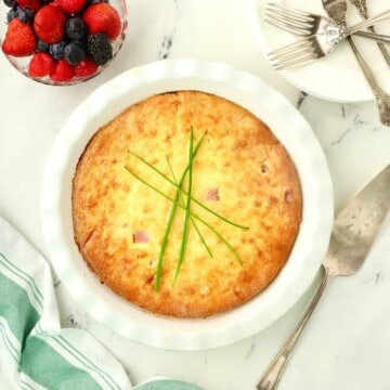 A crustless ham and cheese quiche in a white pie plate.