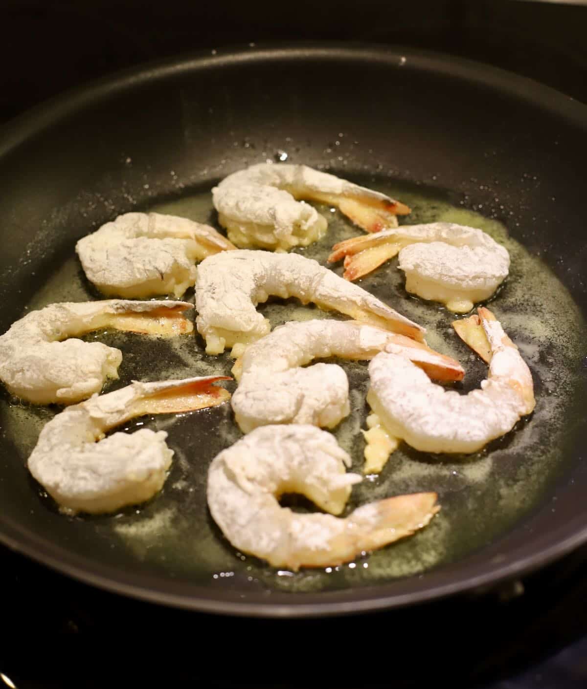 Shrimp coated with flour pan-frying in a skillet. 