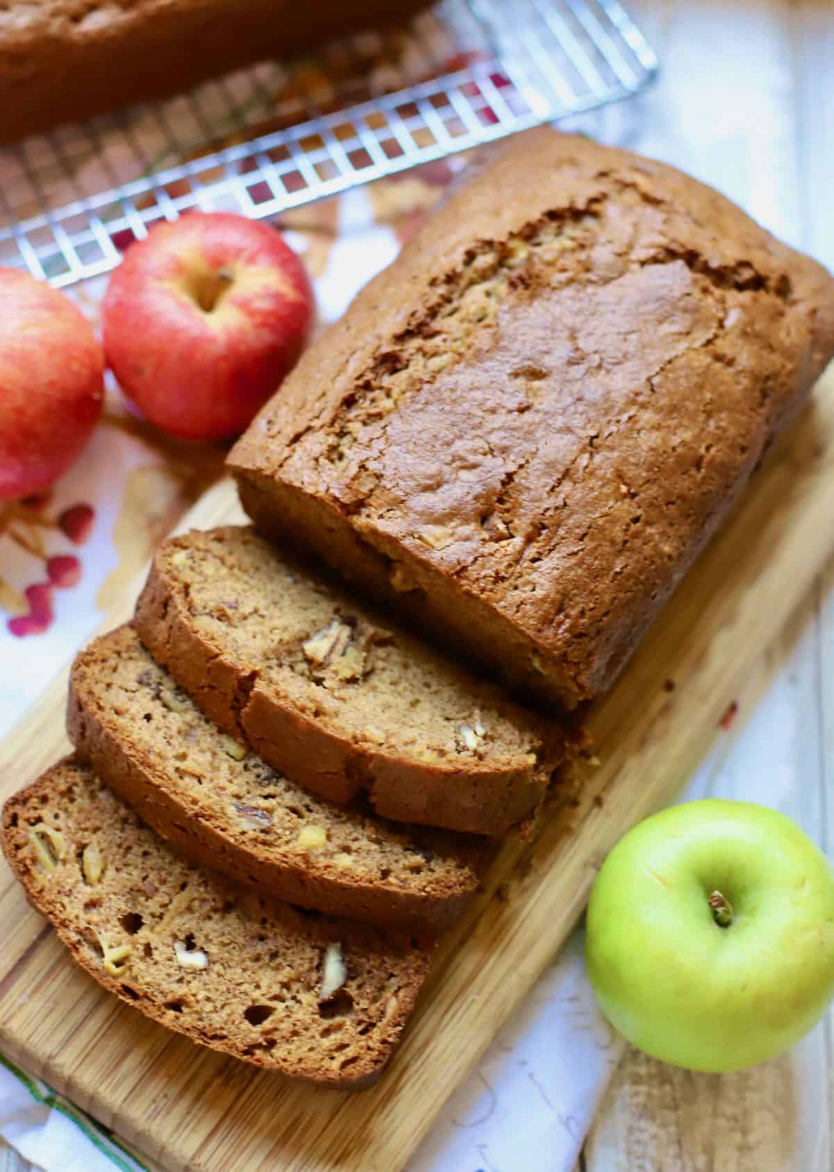 Sliced apple bread with fresh apples next to it. 