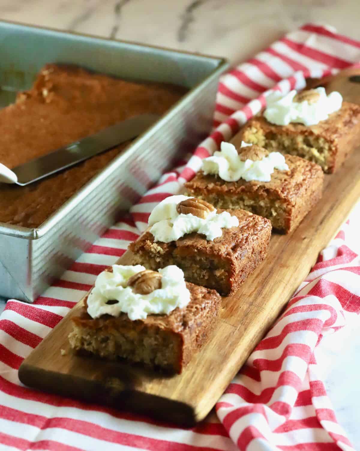 Pecan cake cut into squares and topped with whipped cream. 