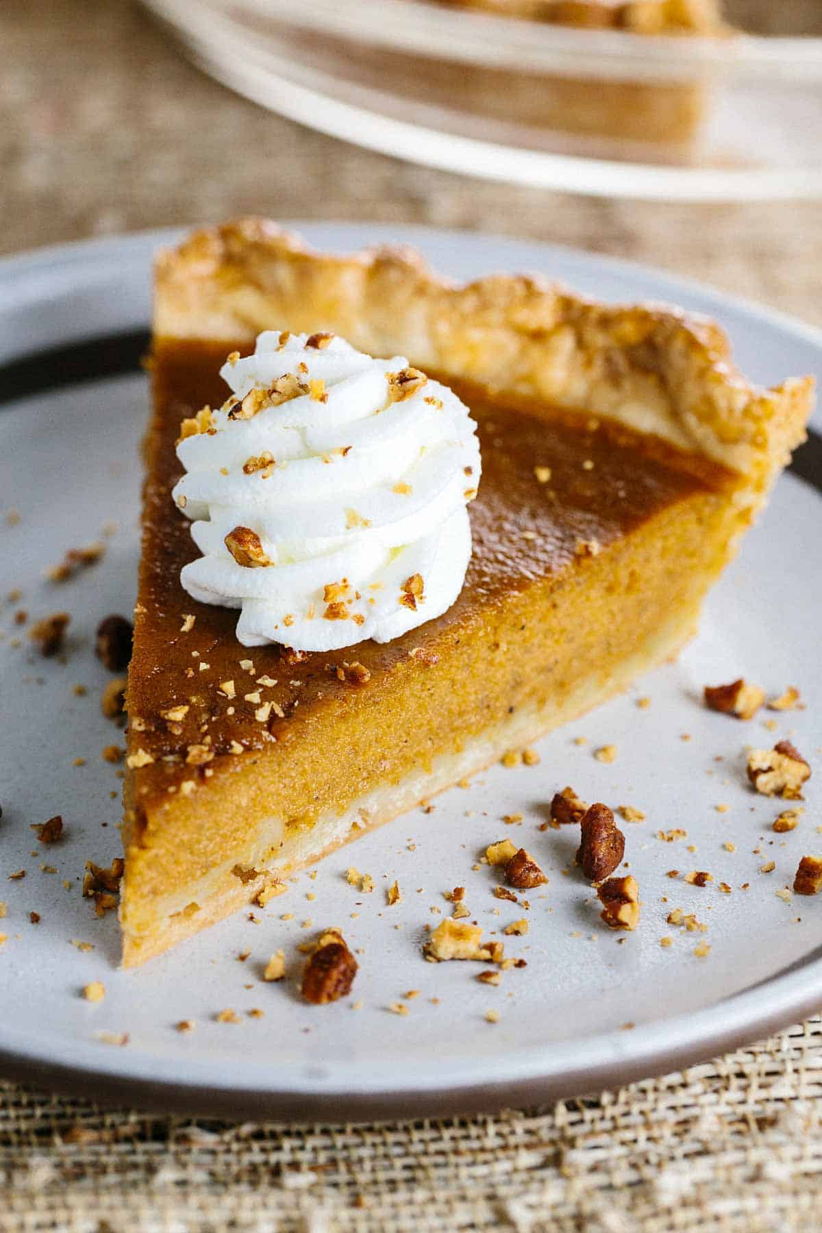 A slice of pumpkin pie topped with whipped cream. 