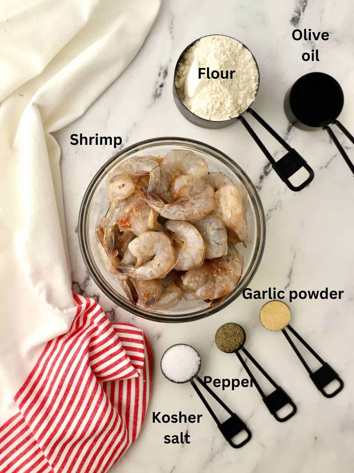 Ingredients to make fried shrimp including raw shrimp and flour. 