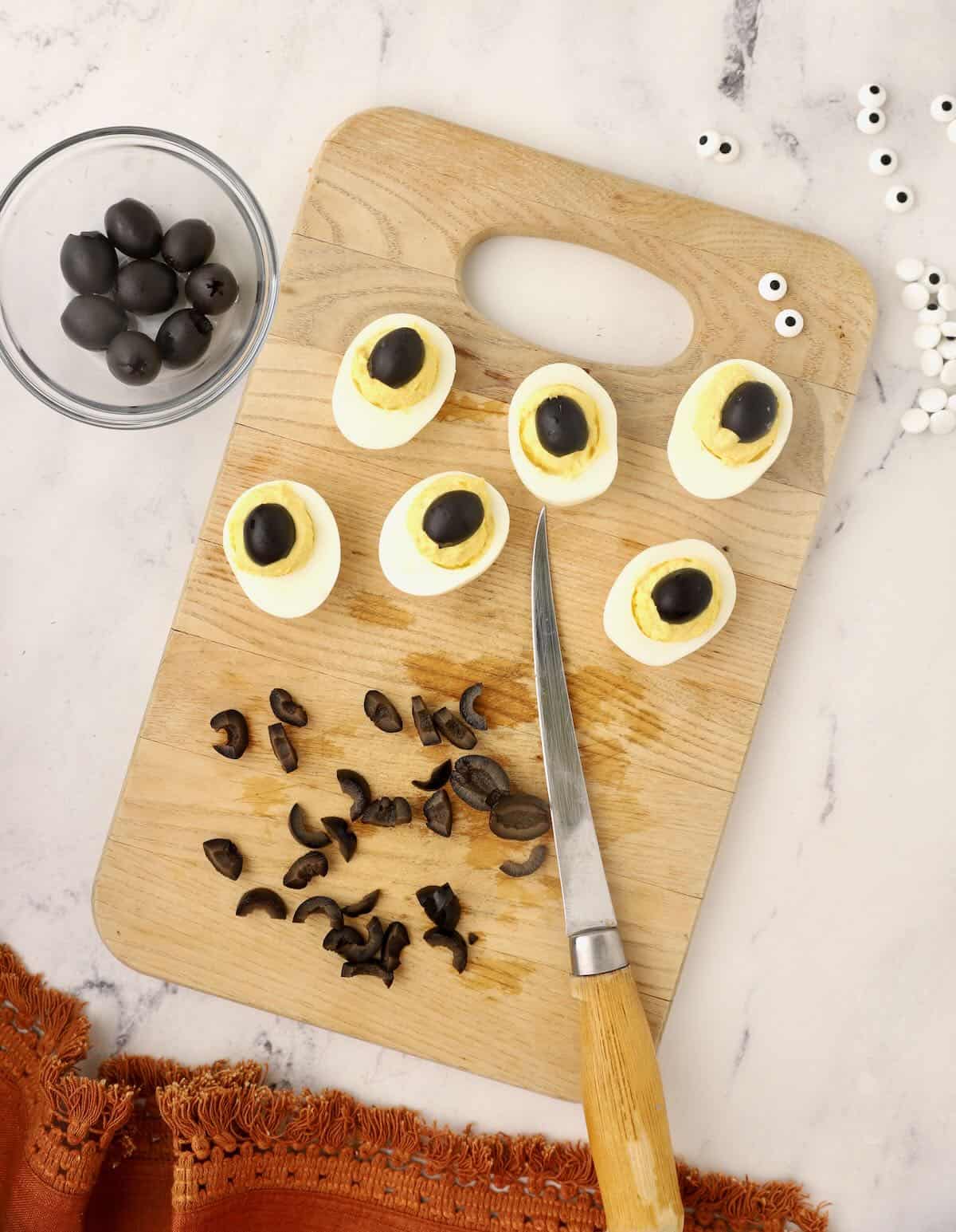 Hard boiled egg halves topped with a half of a black olive. 