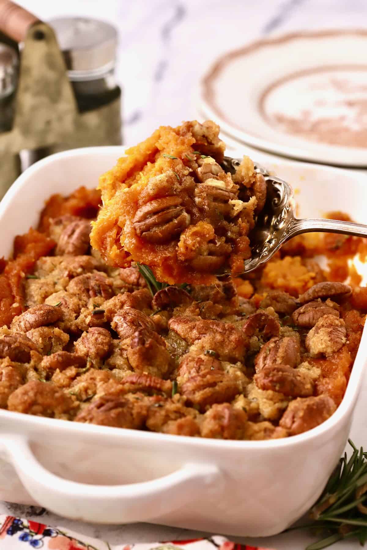 A large spoon with a serving of sweet potato casserole and pecans. 