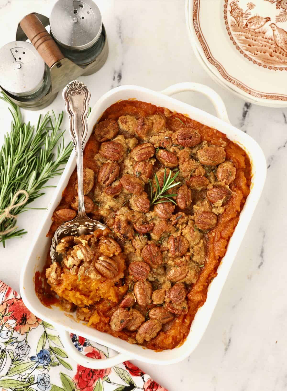 Sweet potato casserole in a white baking dish with a serving spoon.