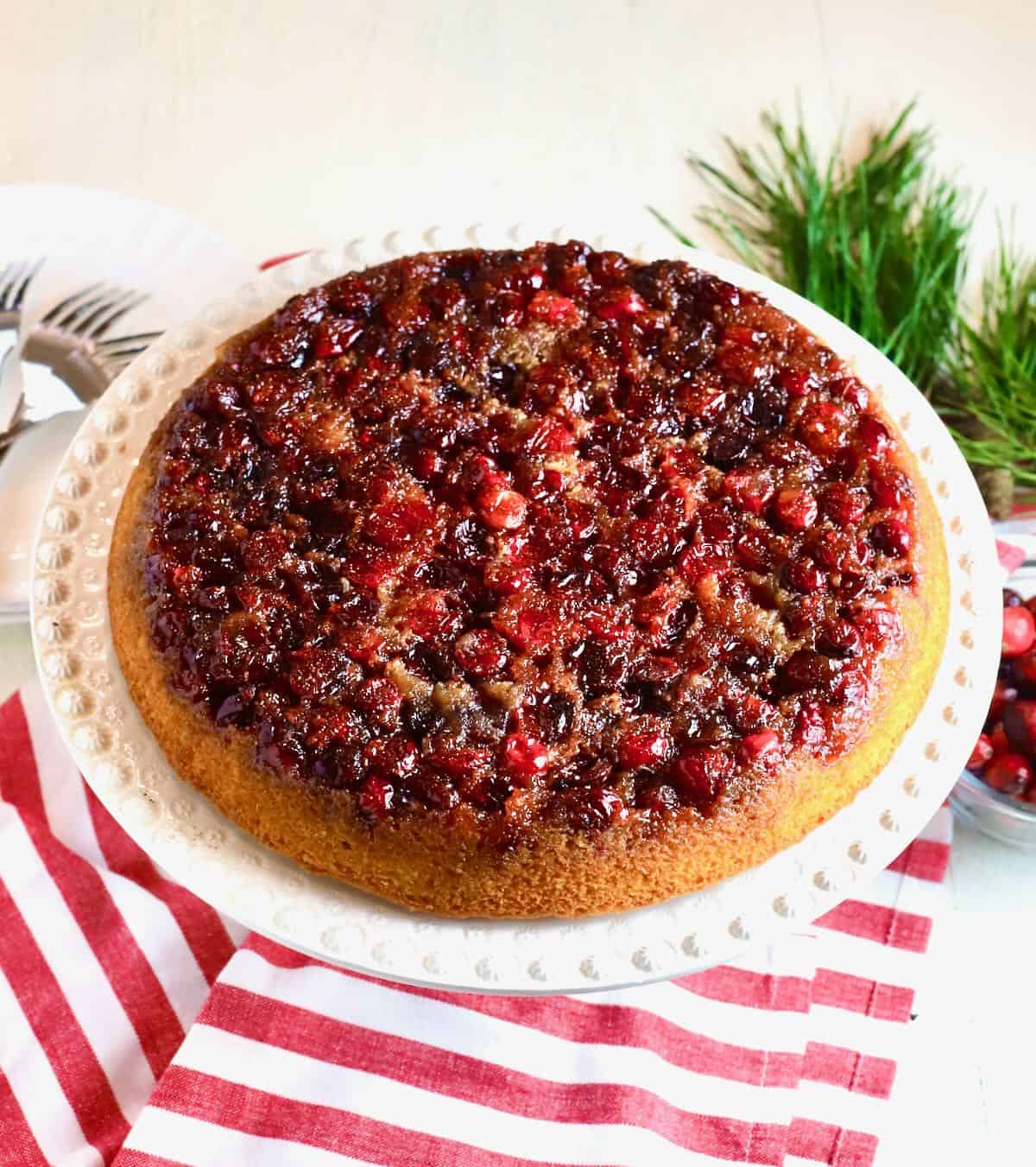 A cranberry upside down cake on a white cake platter. 