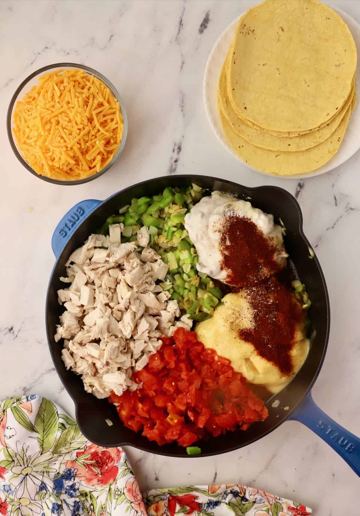 A skillet with cooked chicken, condensed soup, tomatoes and green chilies. 