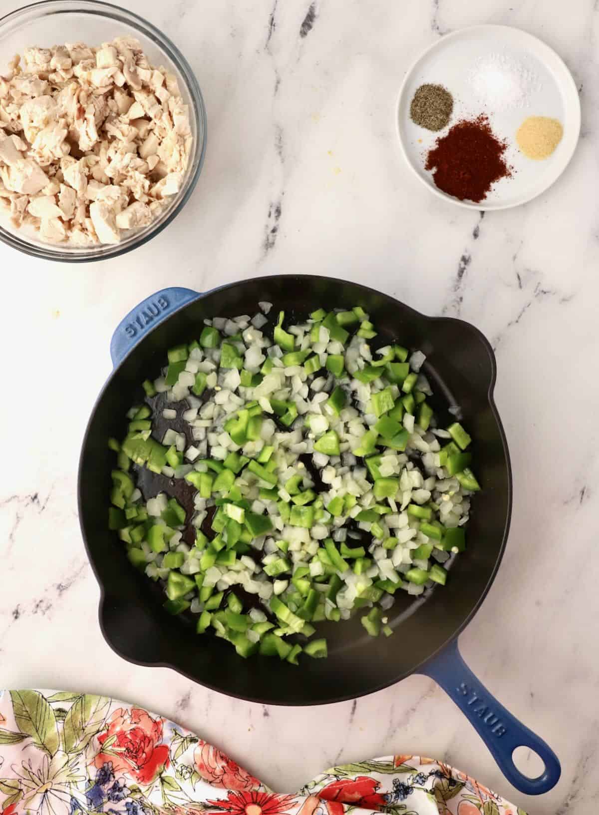 Chopped onions and bell pepper cooking in a skillet. 